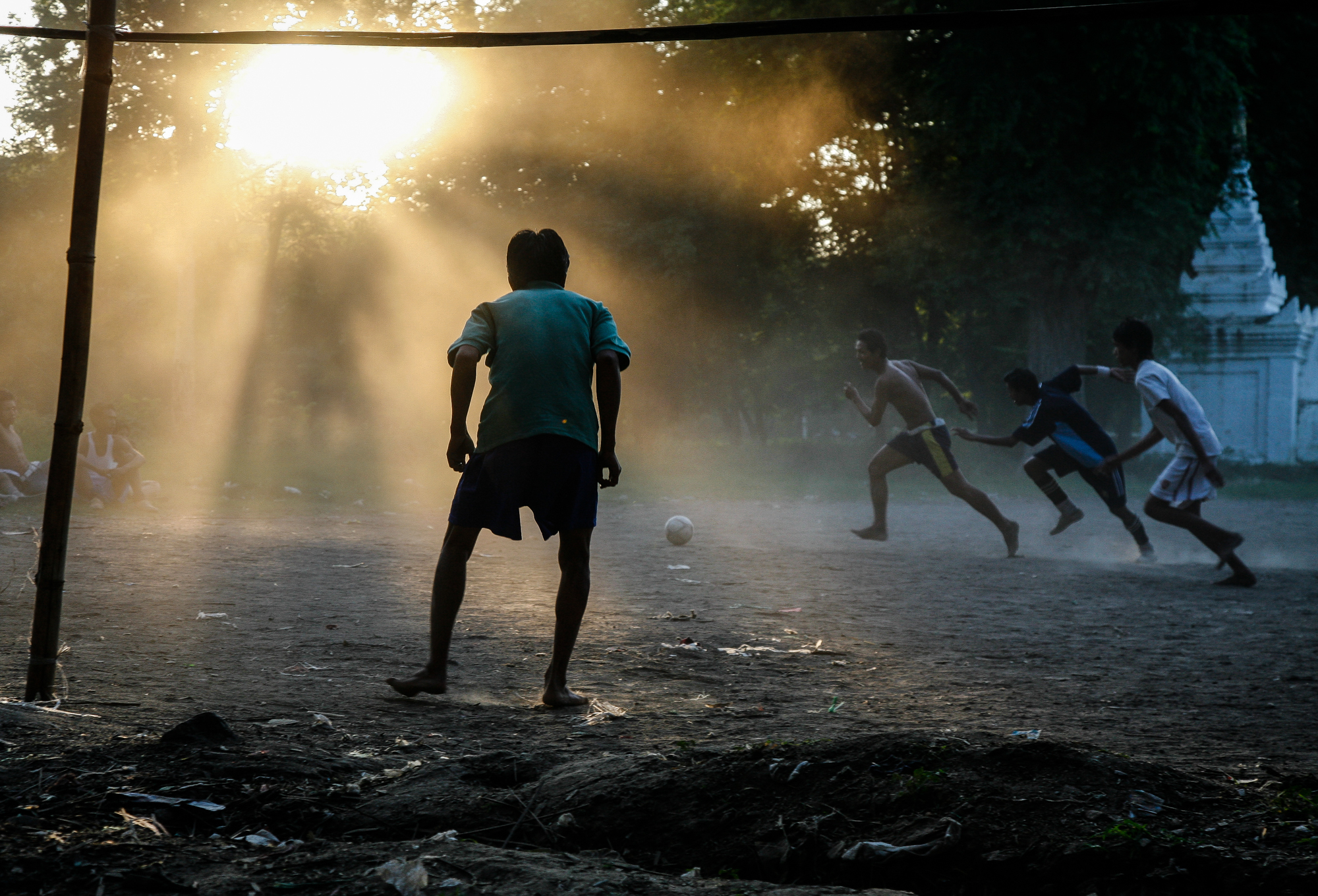 Boys playing football in the dust